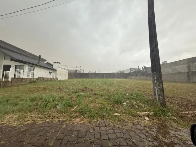 Vista externa de um terreno gramado com cerca no fundo.