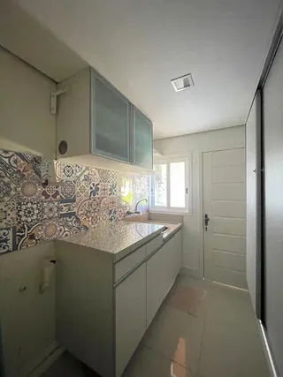 Vista da cozinha com armários e revestimento de azulejos no Brasil.