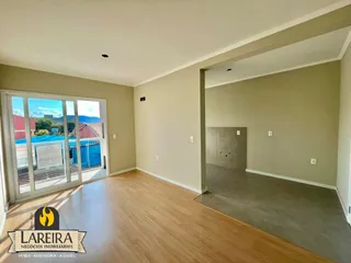 Interior de uma sala ampla com piso de madeira e porta de vidro.