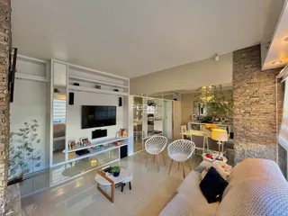 Sala de estar moderna com decoração clara e paredes de pedra aparente.