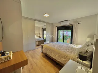 Quarto com piso de madeira e acesso a uma varanda.