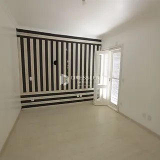 Ambiente interno com parede listrada preta e branca e porta de acesso a outro cômodo.