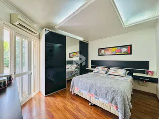 Quarto com piso de madeira e porta de vidro abrindo para a área externa.