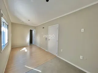 Uma sala com piso de madeira clara e paredes bege.
