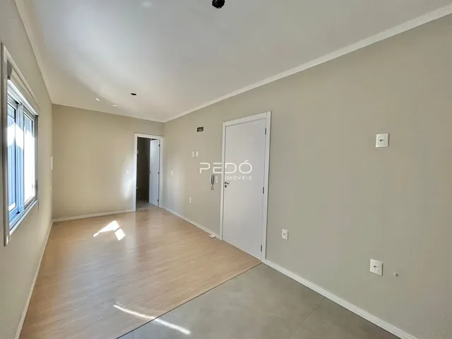 Uma sala com piso de madeira clara e paredes bege.