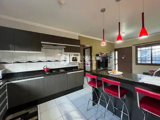 Vista da cozinha com armários escuros e bancadas escuras.