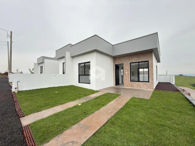 Fachada moderna de uma casa em Lajeado, Brasil, com paredes brancas e detalhes em tijolo aparente.