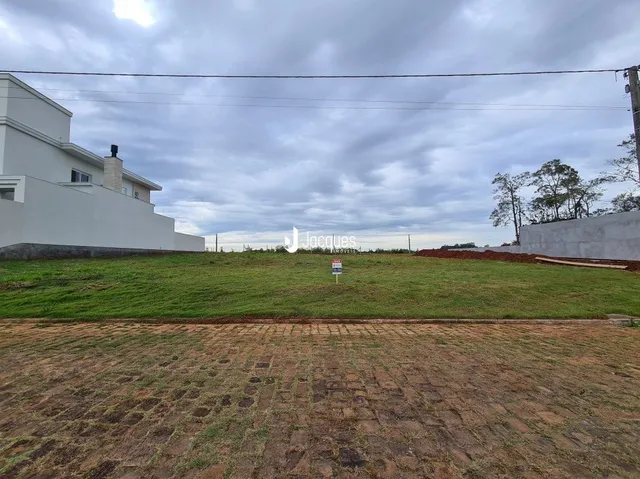 Vista externa de uma propriedade com gramado em primeiro plano e um edifício branco ao fundo.