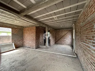 Interior com paredes de tijolo aparente e teto de concreto bruto.