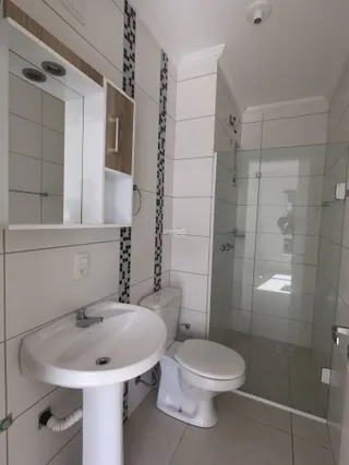 Banheiro com pia, vaso sanitário e box de vidro em um imóvel.