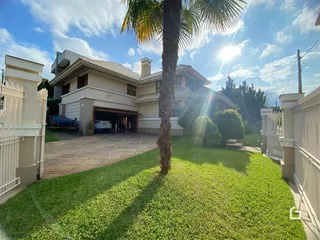 Fachada de uma residência em Lajeado, Brasil, com jardim gramado e árvore em primeiro plano.