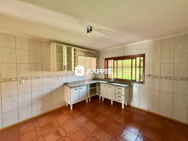 Foto de uma cozinha com armários brancos e piso de terracota.