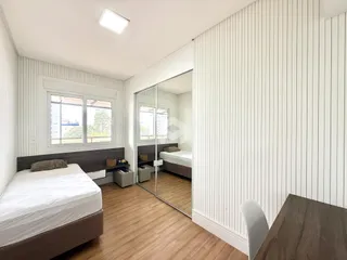 Quarto com piso de madeira e janela de grande porte em Lajeado.