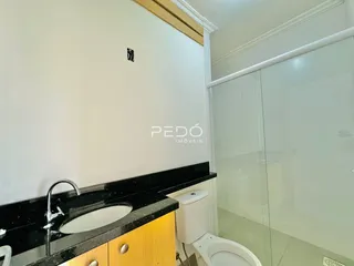 Foto de um banheiro com bancada escura e box de vidro.