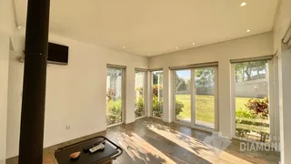 Sala de estar com piso de madeira e grandes janelas que dão para o jardim.