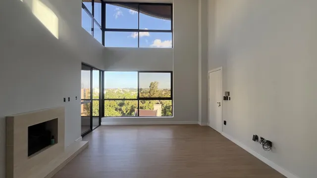 Sala ampla com grandes janelas que proporcionam uma vista panorâmica da paisagem urbana.