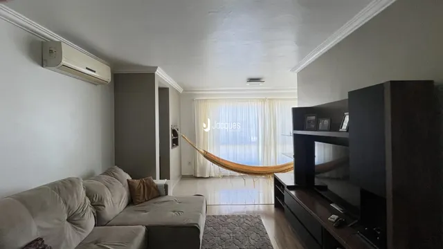 Sala de estar com sofá e macramê pendurado na janela.