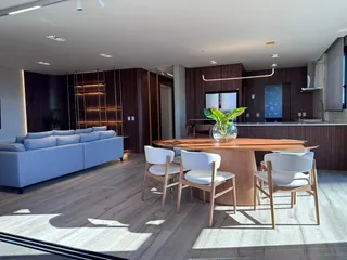Sala de estar moderna com sofá e mesa de jantar de madeira em um apartamento.