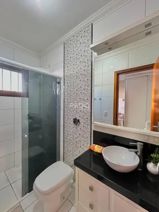 Banheiro com revestimento de azulejos e box de vidro.