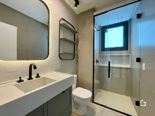 Foto de um banheiro moderno com box de vidro e bancada branca.