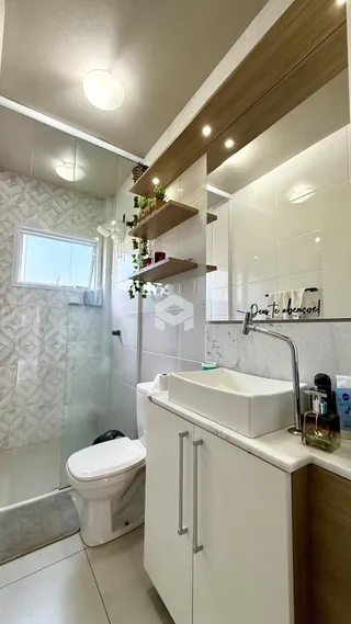 Interior de um banheiro com revestimento branco e vidro.