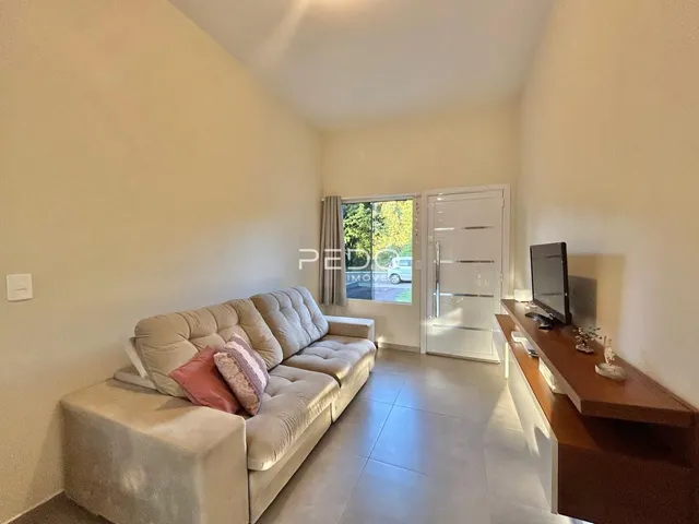 Sala de estar com um sofá e piso de cerâmica claro.