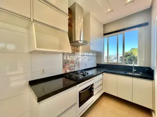 Cozinha moderna com armários brancos e bancadas escuras.