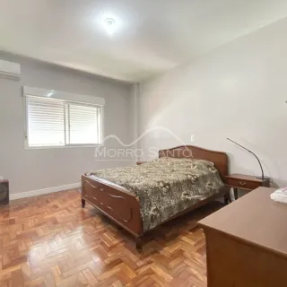 Quarto com cama de madeira e piso de madeira clara.