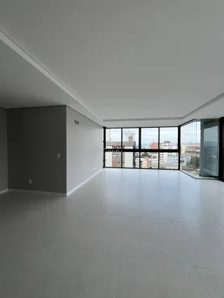 Vista interna de um ambiente amplo com piso claro e grandes janelas.