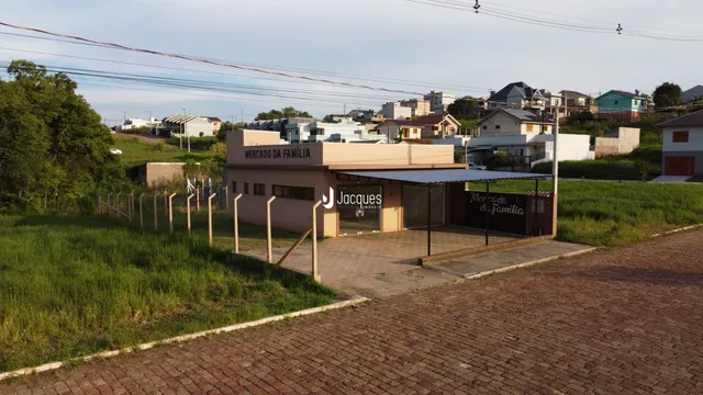 Fachada de um prédio comercial em Lajeado, Brasil, com área verde ao redor.