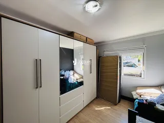 Quarto com armários brancos e piso de madeira em um imóvel em Lajeado.