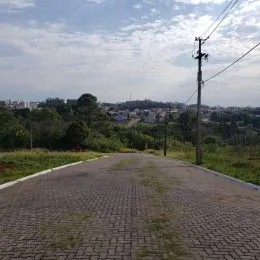 Uma estrada pavimentada leva a uma área verde com vegetação ao fundo.