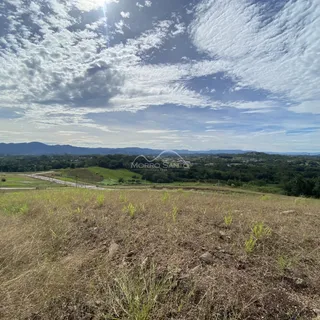 Vista panorâmica de uma paisagem rural com colinas e vegetação sob um céu parcialmente nublado.