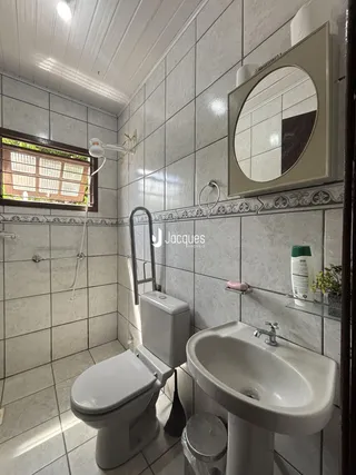 Foto interna de um banheiro com revestimento cerâmico e louças sanitárias brancas.
