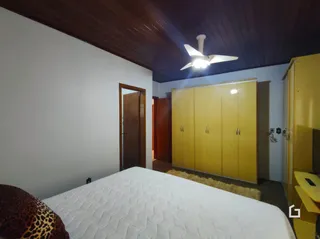 Quarto com cama e teto de madeira em uma residência.