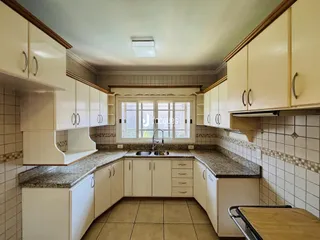 Vista interna de uma cozinha com armários brancos e bancadas de granito.