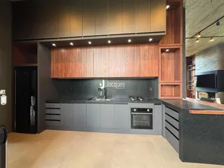 Interior de uma cozinha moderna com armários de madeira e bancadas escuras.
