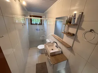 Banheiro com revestimento branco e bancada de madeira.