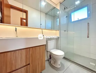 Banheiro com box de vidro e revestimento claro.