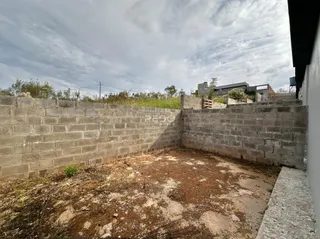 Vista externa de um terreno com muros de concreto e solo seco.