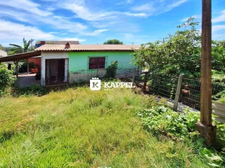 Fachada de uma casa verde com grama alta no primeiro plano.