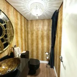 Sala de estar com parede decorada em papel de parede dourado e lustre no teto.