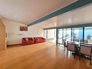 Sala de estar com piso de cerâmica e sofás vermelhos que se abre para uma área externa.