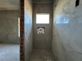 Interior de um espaço com paredes de concreto aparente e uma porta de tijolo aparente.
