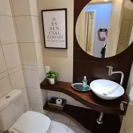 Foto de um banheiro com revestimento claro e louças brancas.