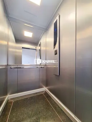 Corredor interno com revestimento metálico nas paredes.
