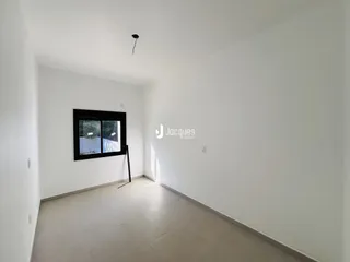 Hall de entrada com paredes brancas e piso claro.