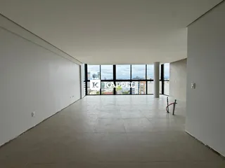 Ambiente amplo com piso claro e grandes janelas que oferecem vista para a cidade.