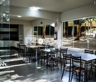 Sala de estar com mesas e grandes portas de vidro que dão acesso ao exterior.