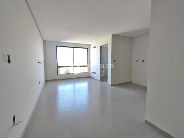 Interior de uma sala ampla com paredes brancas e piso claro.